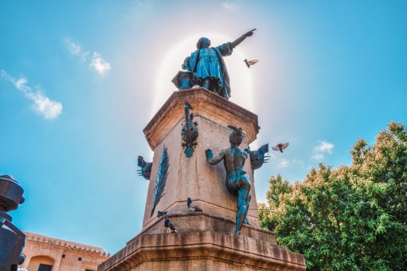 Sonnenumrahmter Standpunkt einer Statue mit einer Figur, die nach oben zeigt.