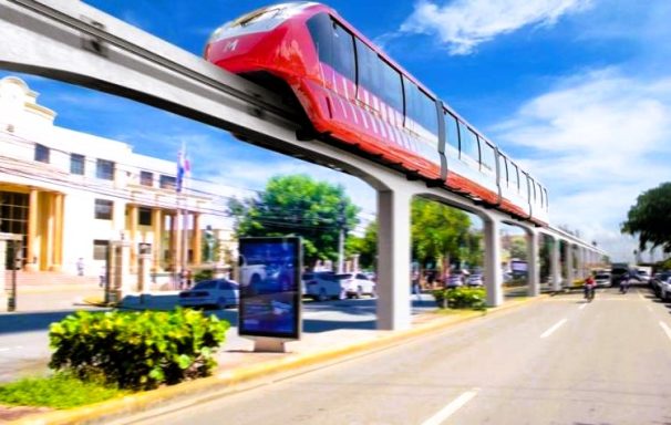 Monorail verläuft über eine Straße mit modernen Gebäuden und Bäumen im Hintergrund.